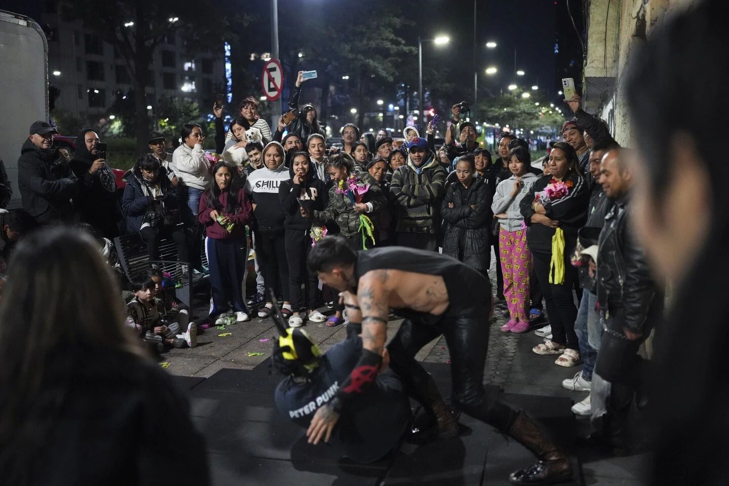 Los vecinos, ven la actuación de dos luchadores organizada por voluntarios que se hacen llamar, los Reyes Punk mientras distribuyen, juguetes, ropa y piñatas a niños desfavorecidos. Foto: AP