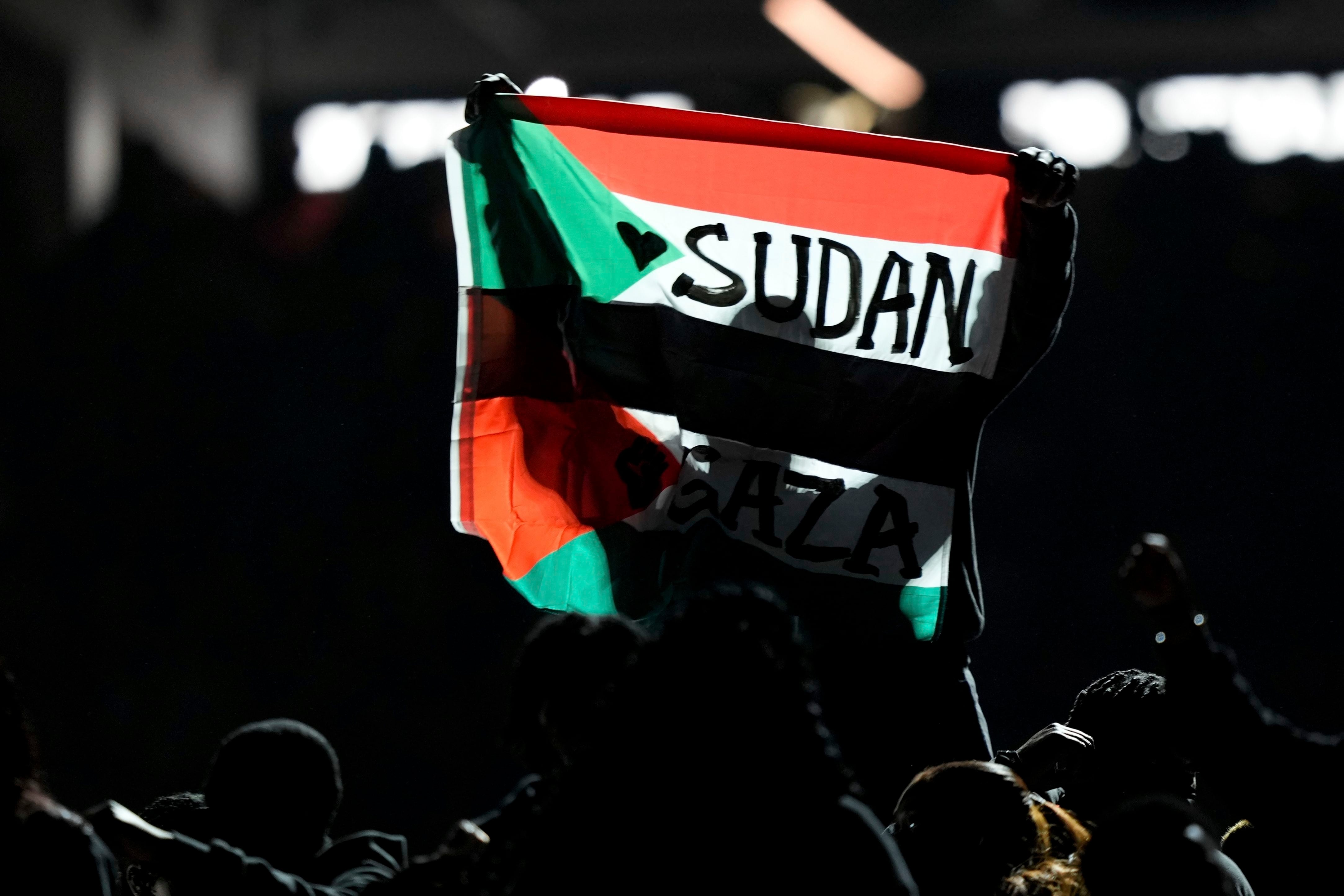 Un individuo alza una bandera que menciona a Sudán y Gaza durante el descanso del Super Bowl, el domingo 9 de febrero de 2025, en Nueva Orleans. (AP Foto/Matt Slocum)