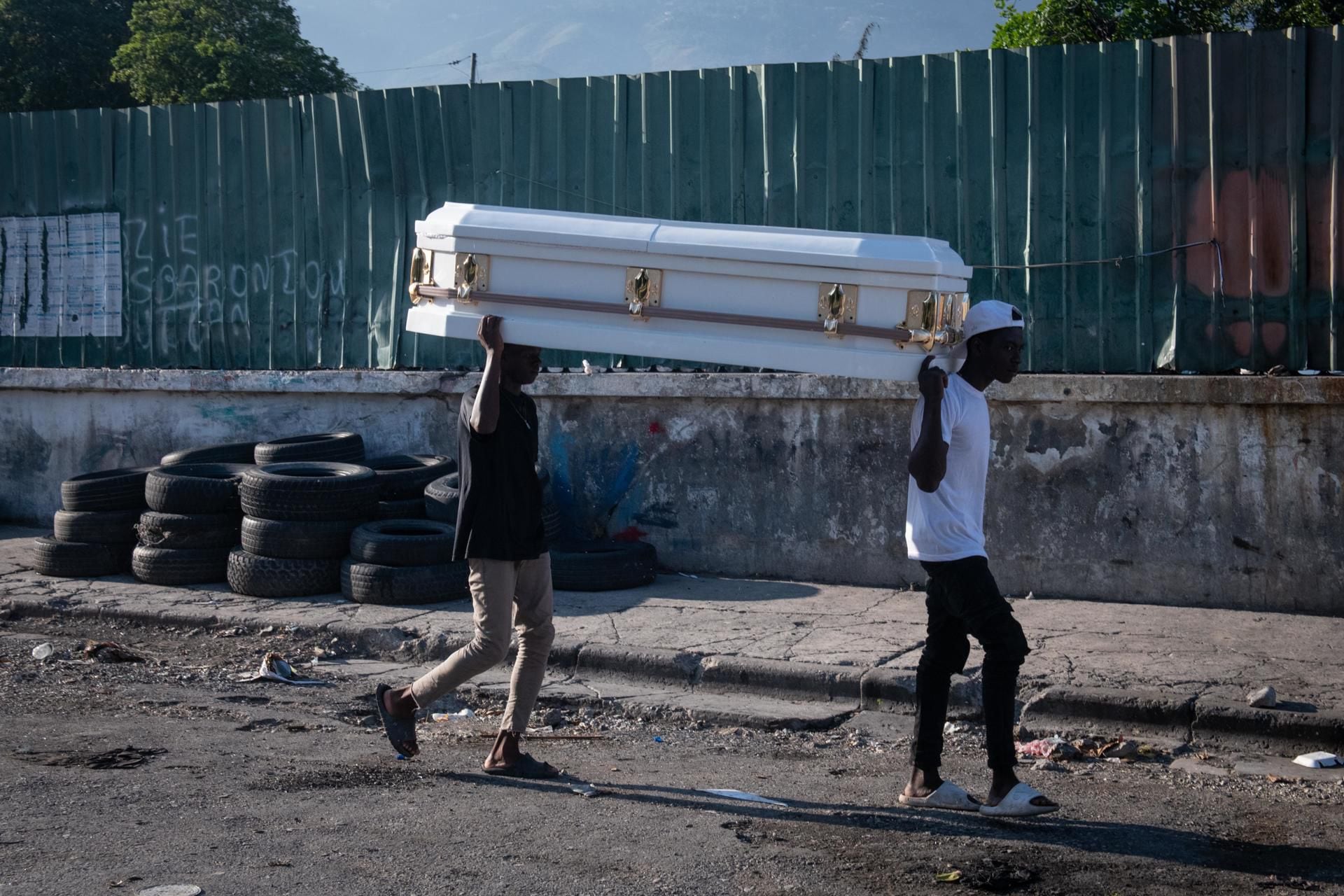 Dos hombres cargan un ataúd tras jornada violenta en Puerto Príncipe. (Foto: Johnson Sabin/EFE)