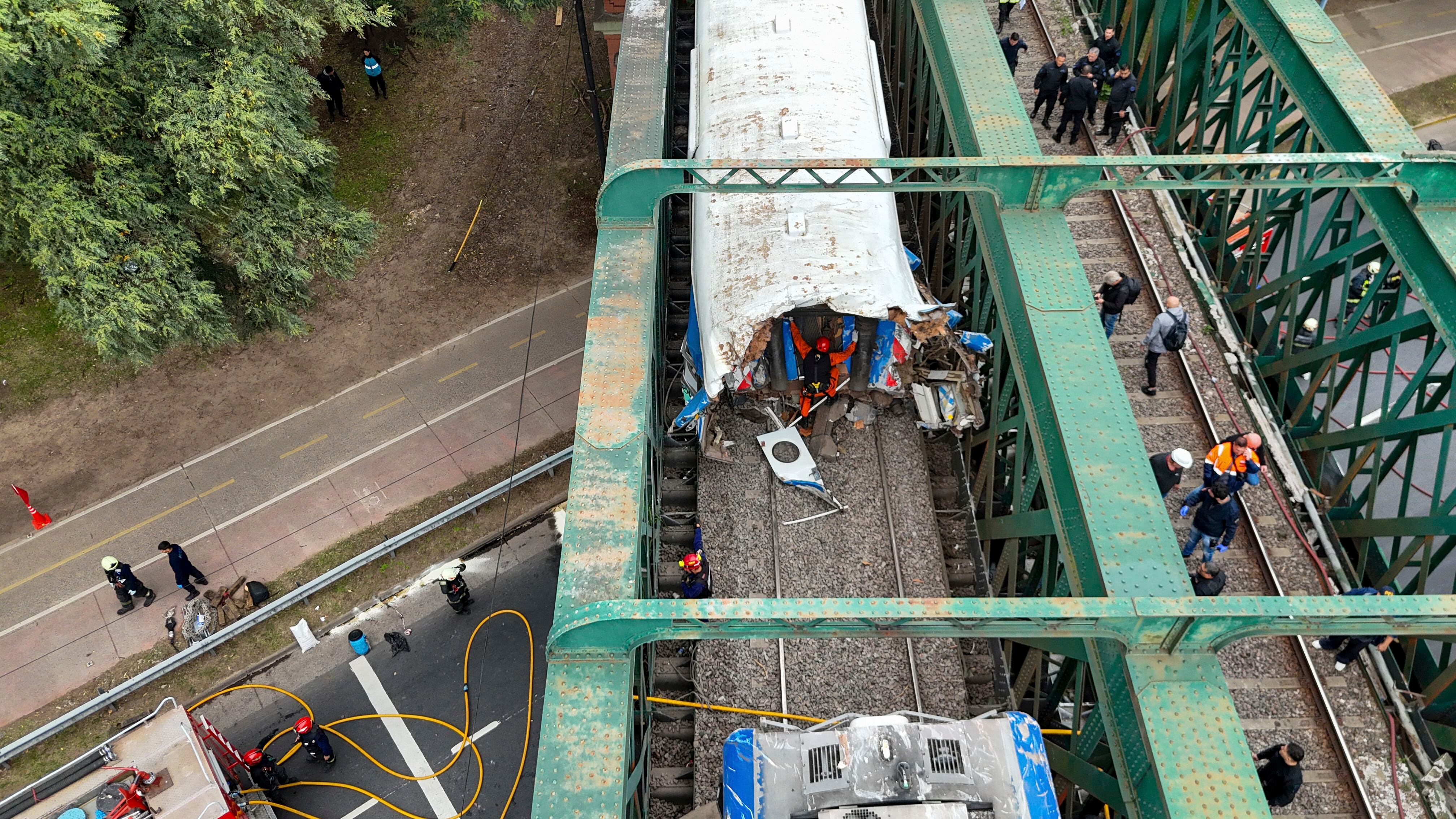 Railroad workers inspect a passenger train after it collided with another in Buenos Aires