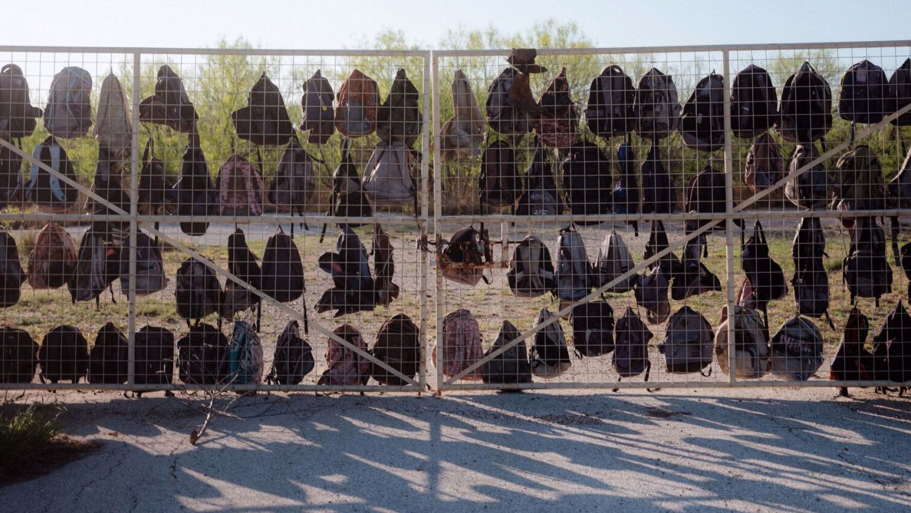 Mochilas de migrantes detenidos por policías cuelgan de la valla de un rancho cerca de Eagle Pass.