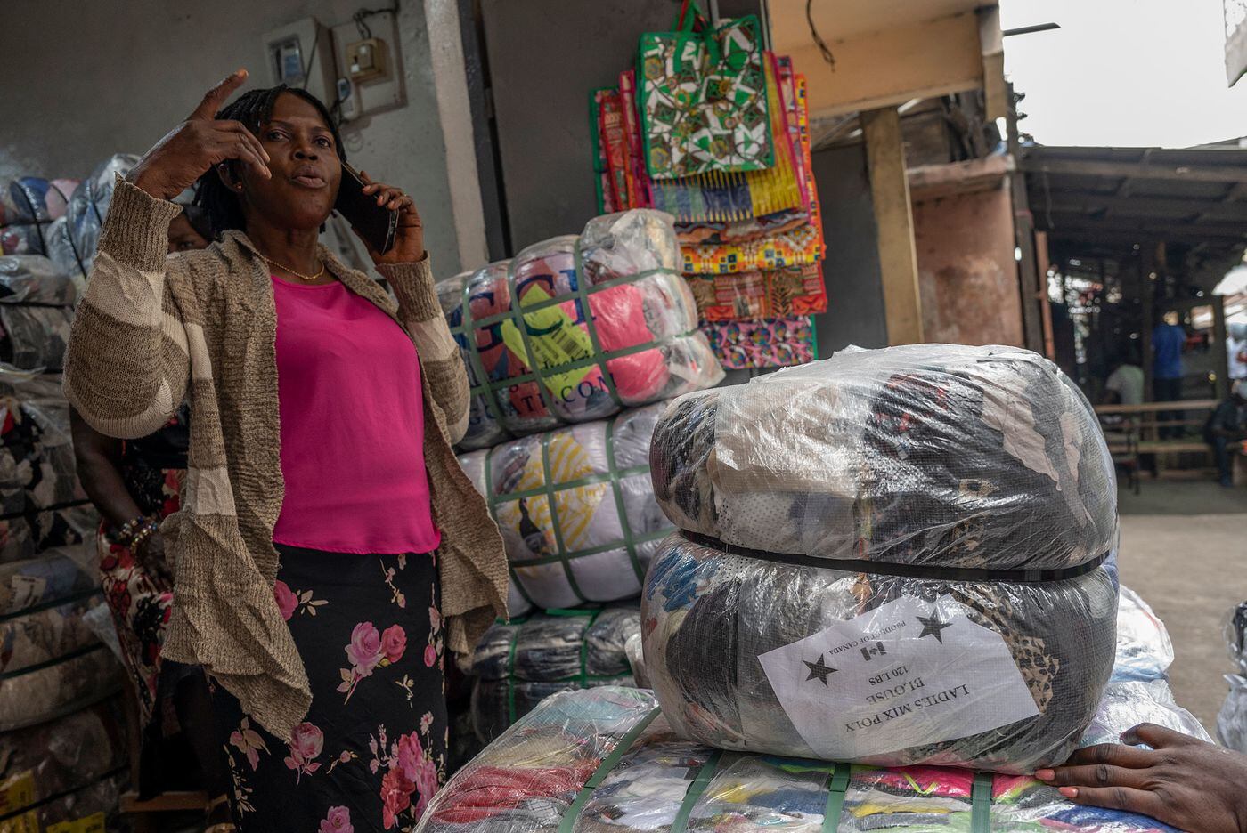 Una vendedora habla frente a paquetes con ropa de segunda mano en Accra, la capital de Ghana.