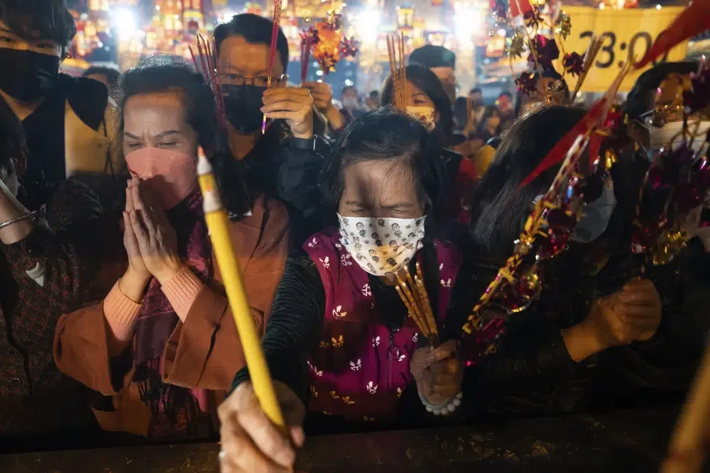 Fieles con mascarillas preden sus primeras varitas de incienso mientras rezan en el templo Wong Tai Sin de Hong Kong, el sábado 21 de enero de 2023, para celebrar el inicio del Año Nuevo Lunar.