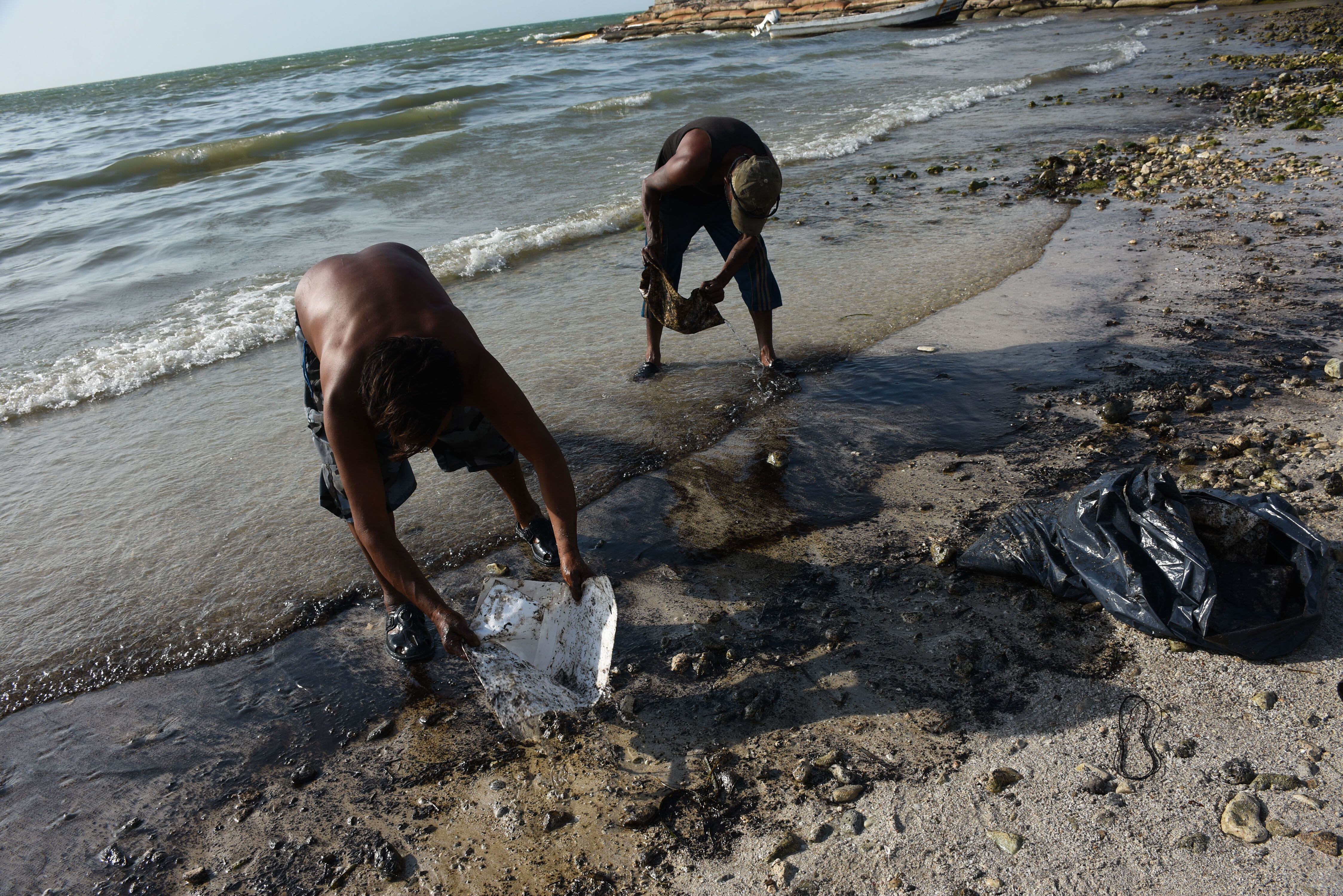 Trabajadores limpian los residuos de aceite que llegaron a las playas.