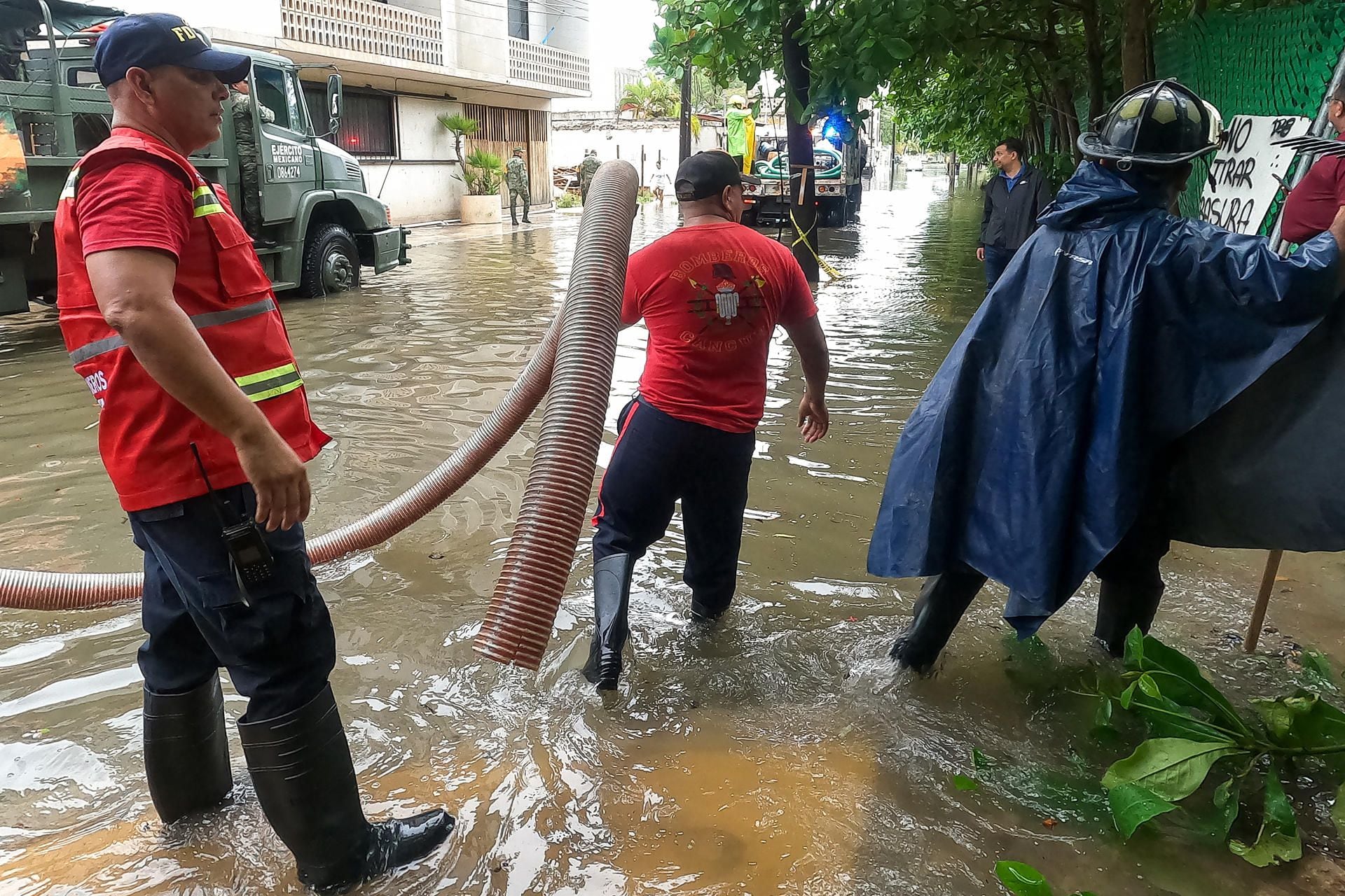 Personal de Protección Civil trabaja en una calle inundada debido a las fuertes lluvias, este martes en Cancún