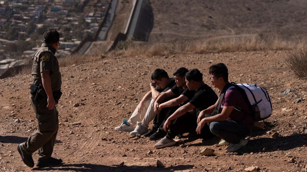 El agente Gutierrez de la patrulla fronteriza pasa junto a cuatro hombres detenidos tras cruzar la frontera de Estados Unidos de forma ilegal a través de un hueco entre los dos muros que separan México del país. AP