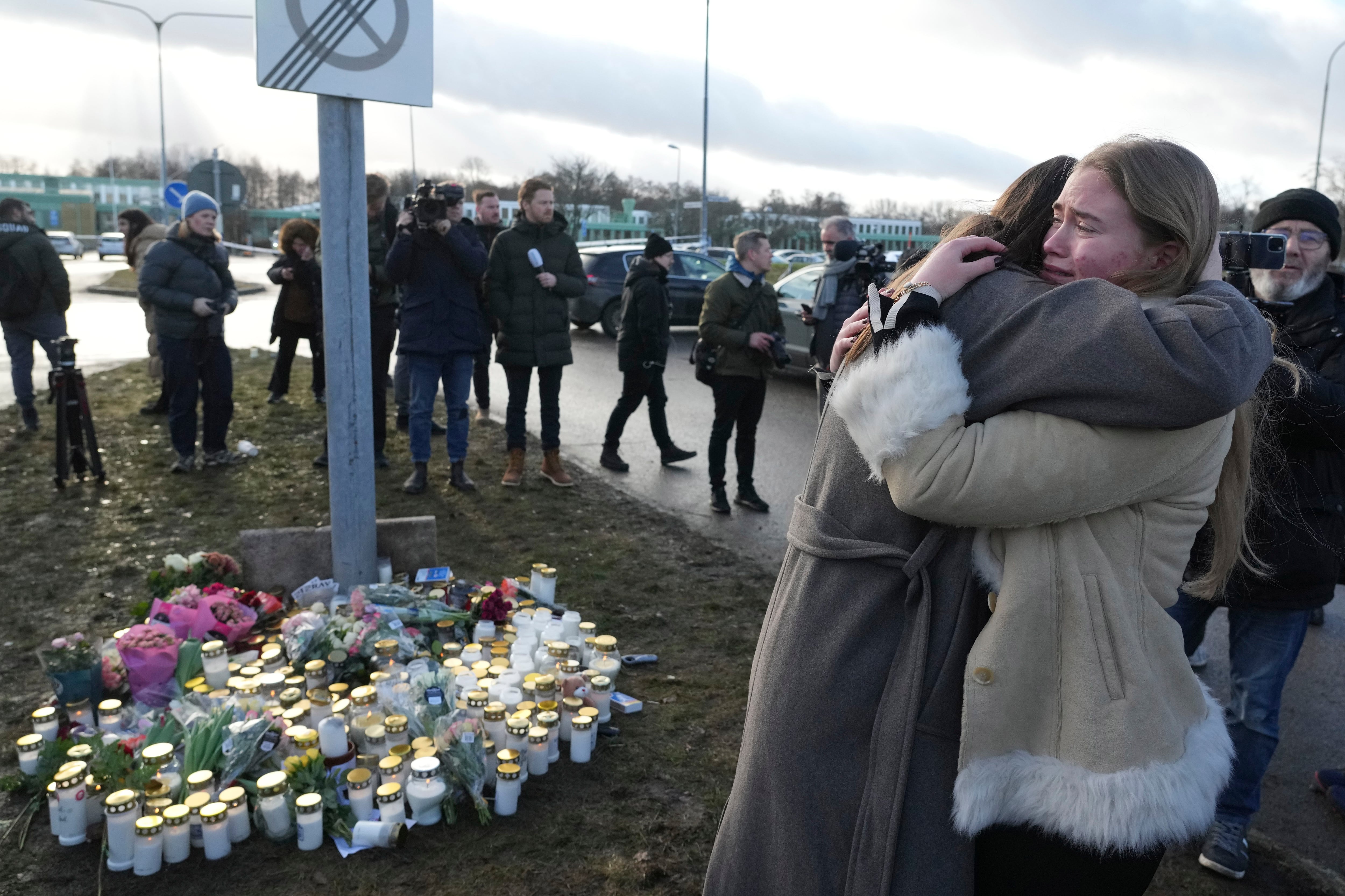 Un grupo de personas se congregan en un monumento improvisado para recordar a las víctimas de un tiroteo en un centro educativo para adultos en Suecia.