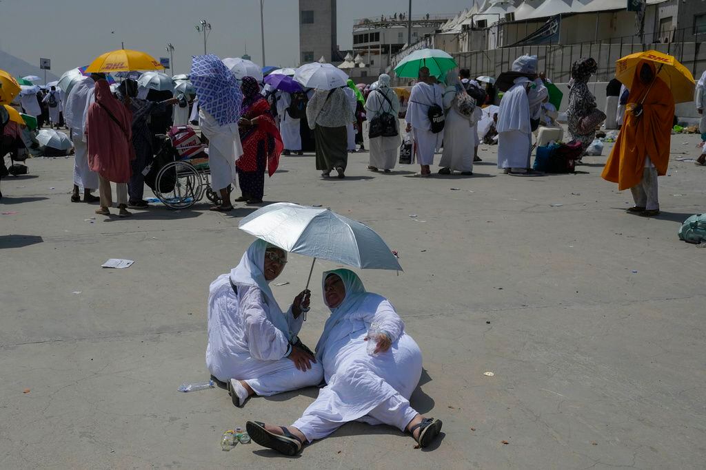 Dos peregrinas musulmanas se protegen del sol cerca de los pilares donde se realiza la lapidación simbólica del diablo, el último ritual del haj, en Mina, cerca de La Meca, Arabia Saudí, el 16 de junio de 2024. (AP Foto/Rafiq Maqbool)