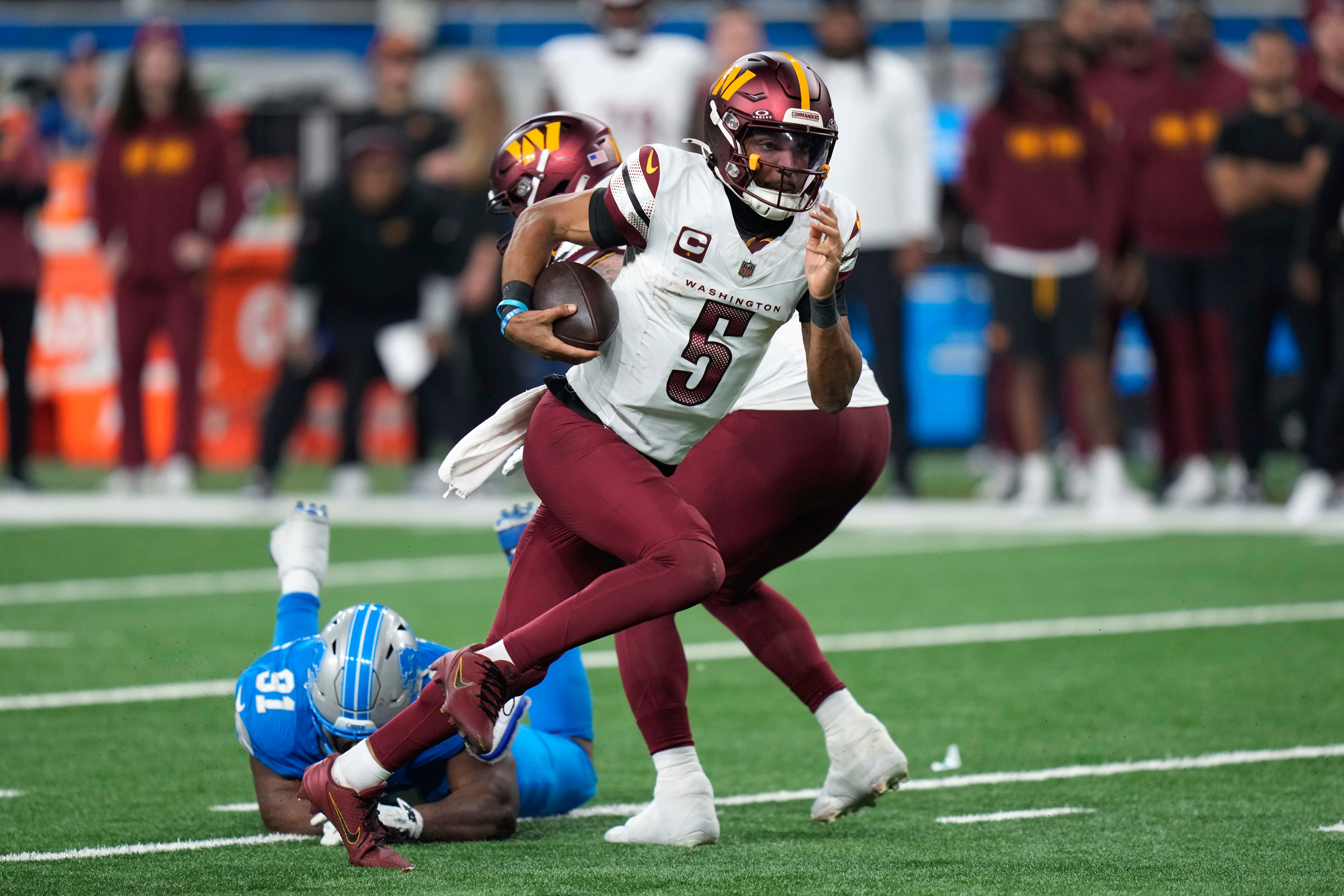 Jayden Daniels, quarterback de los Commanders de Washington, acarrea el balón frente a Levi Onwuzurike, de los Lions de Detroit, en el partido de playoffs disputado el sábado 18 de enero de 2025 (AP Foto/Seth Wenig)