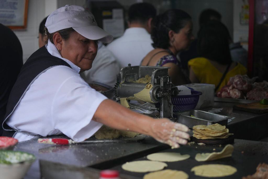 Una empleada lanza una tortilla a la plancha en la taquería Tacos El Califa de León en Ciudad de México.