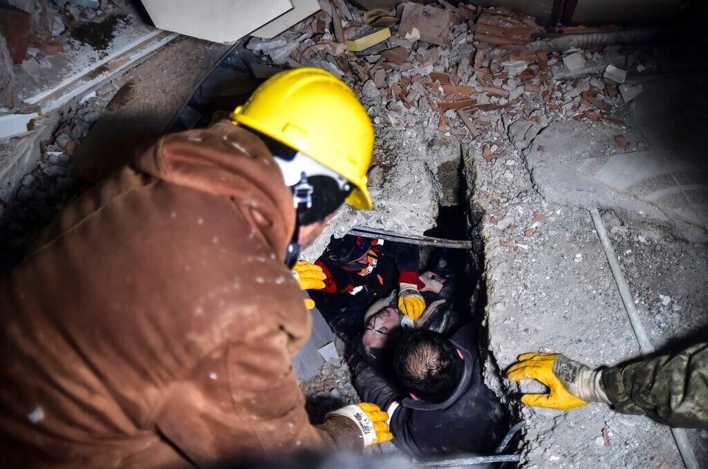 Equipos de emergencia rescatan a una mujer de entre los escombros de un edificio que se vino abajo tras un sismo, en Elbistan, Kahramanmaras en Turquía. 