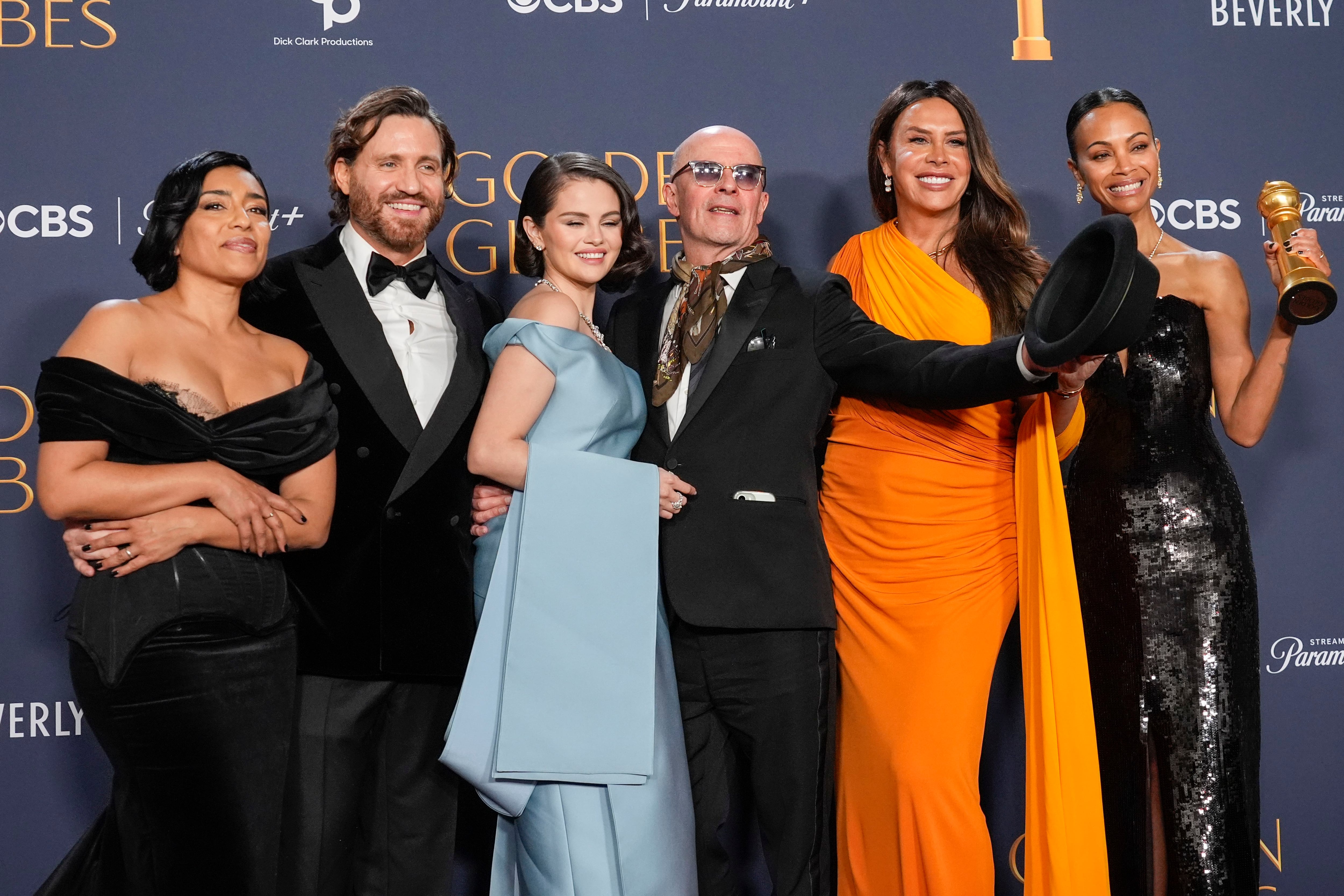 Adriana Paz, de izquierda a derecha, Édgar Ramírez, Selena Gomez, Jacques Audiard, Karla Sofía Gascón y Zoe Saldaña posan en la sala de prensa con el premio a la mejor película musical o de comedia por 