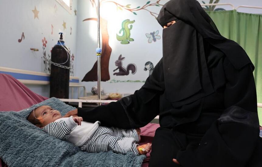 Salwa sentada en la cama de su nieto en el hospital materno-infantil Al-Qanauis.