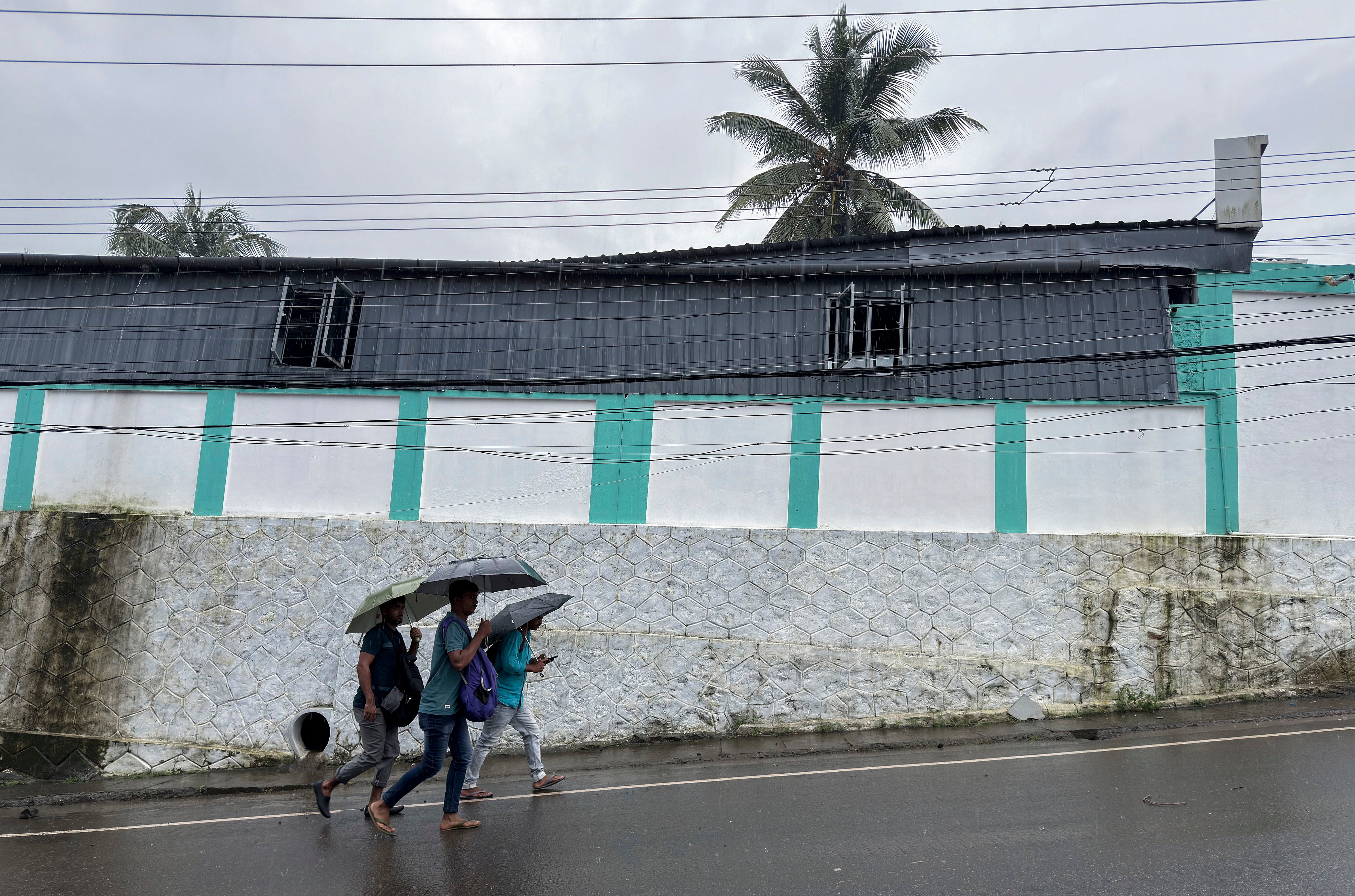 Unas personas salen a trabajar con paraguas en un día lluvioso en Kochi, en el estado de Kerala, India, el martes de 30 de julio de 2024. (AP Foto/ R S Iyer)