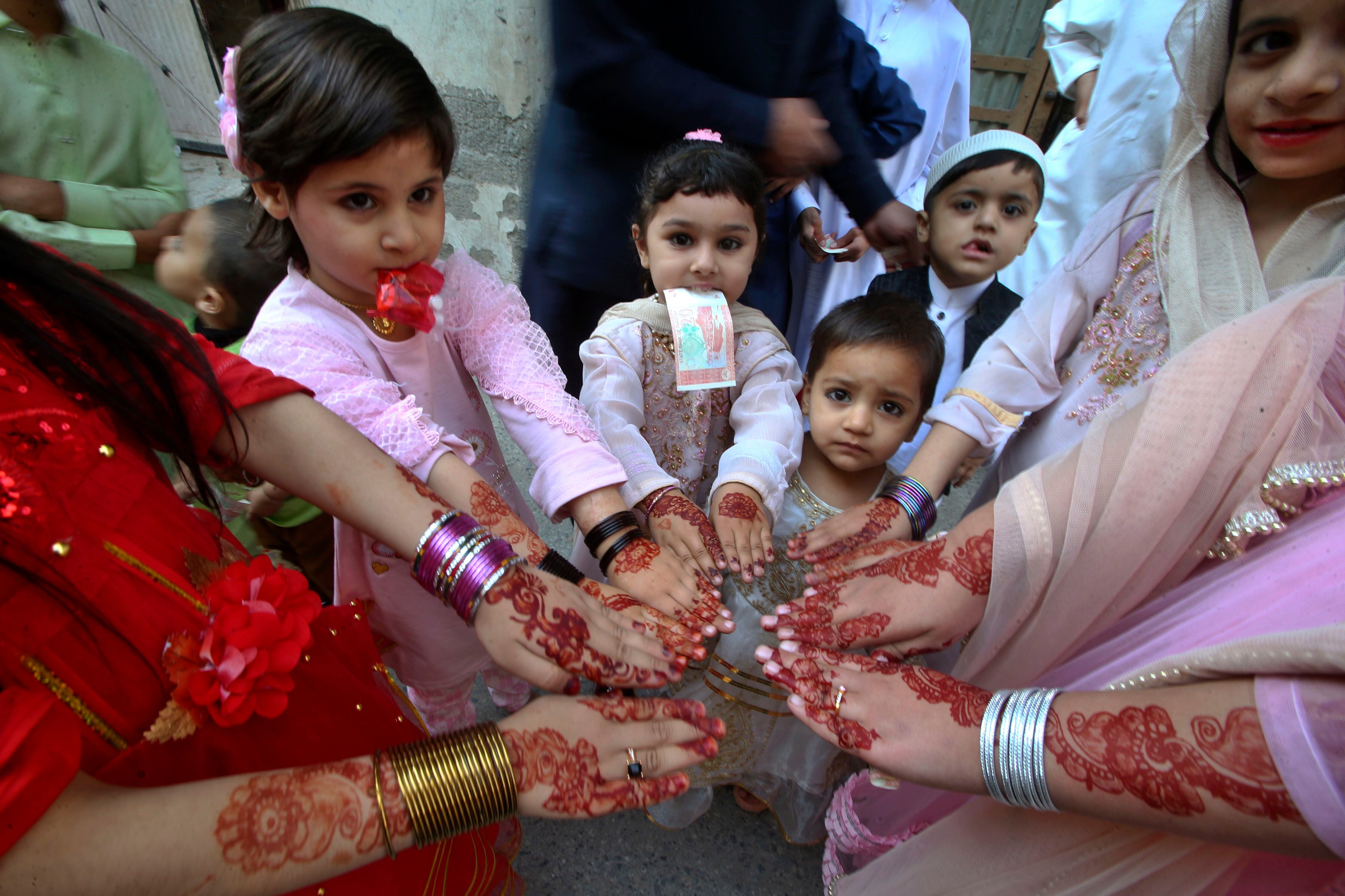 Niñas musulmanas muestran sus manos pintadas con henna con diseños tradicionales para celebrar el Eid al-Fitr, que marca el final del Ramadán, en Peshawar, Pakistán, el miércoles 10 de abril de 2024.