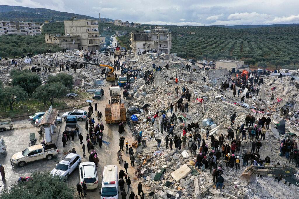 Trabajadores de defensa civil y residentes buscan entre los escombros de edificios derrumbados en el pueblo de Harem, provincia Idlib, Siria.