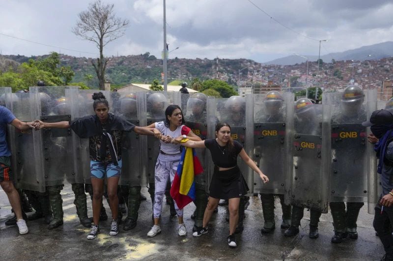 Los residentes intentan bloquear una calle para protestar por los resultados oficiales el día después de las elecciones presidenciales, mientras la Guardia Nacional trabaja para retirarlos en Caracas. Foto: AP